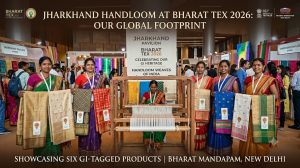 Group of tribal women artisans proudly showcasing Jharkhand's six GI-tagged handloom silk sarees and fabrics around a traditional wooden handloom at the Jharkhand Pavilion in Bharat Tex 2026, Bharat Mandapam, New Delhi.